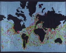 A fabric sewn map of the world. There are sequins sewn onto the piece that represent global trade networks.