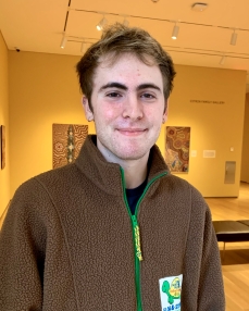 A young man with dark blond hair and brown eyes. He is smiling at the camera.