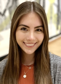 A young woman with fair skin, brown hair, and brown eyes smiles at the camera.