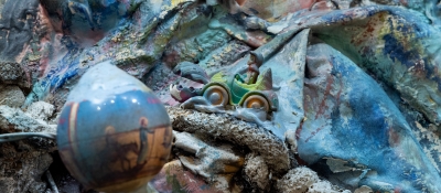 A detail of a sculptural 3D painting that employs cloth, paint, and various found objects.