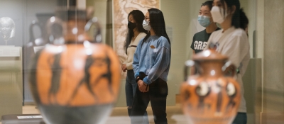 Students wearing surgical masks look at art in a museum gallery.