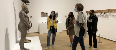 A group of college-aged students on a tour of an exhibition featuring contemporary Native American ceramic art.