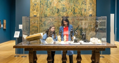 Two visitors look into a glass case full of sculptures.