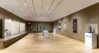 A gallery installed with works of traditional Japanese art. Including hanging scrolls, a hand scroll, and screens.