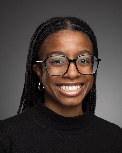 headshot of Evonne Fuselier, a young woman wearing glasses and a black shirt. 