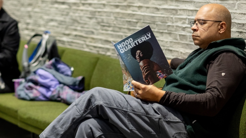 Person sits and reads a magazine called "Hood Quarterly"