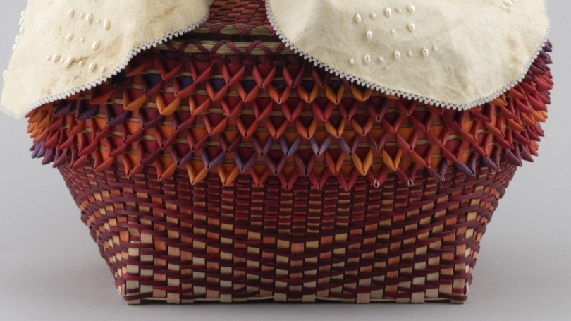 A colorful woven basket with tanned hide laying on top.