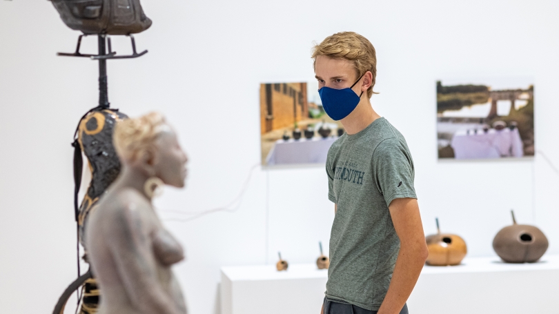 A college-aged man explores an exhibition of contemporary Native American art and ceramics.