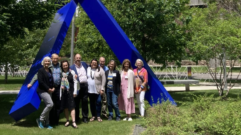 The Director's Circle poses in front of "For Jennifer" by Joel Shapiro, a large blue sculpture.