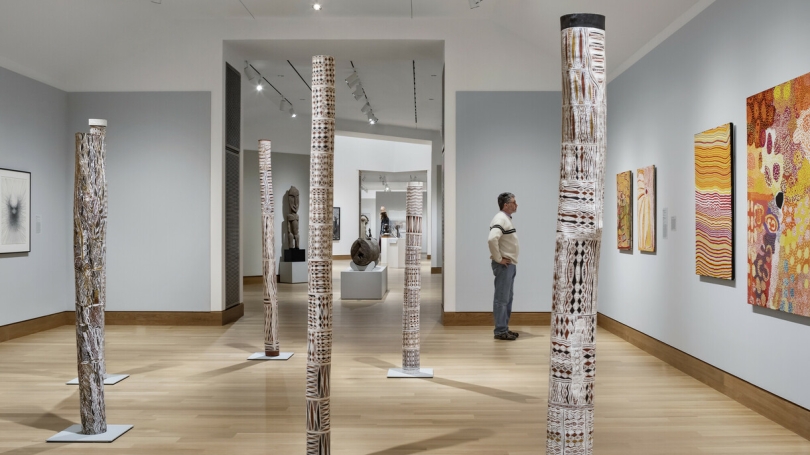 An installation of contemporary Aboriginal Australian art at the Hood Museum of Art. A man stands to the right and admires the art on the wall.