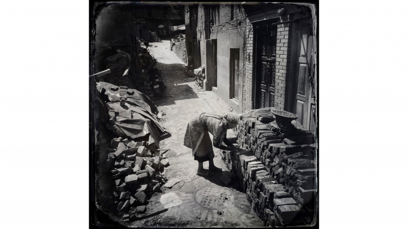 Kevin Bubriski, Latna Maya and her husband spent long days sorting bricks from their collapsed house. Broken pieces went to the left; usable bricks she lovingly stacked to the right, Bhaktapur, Nepal, 2015, archival pigment digital print.