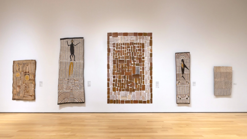 Five large-scale Indigenous Australian bark paintings hang on a white wall. 