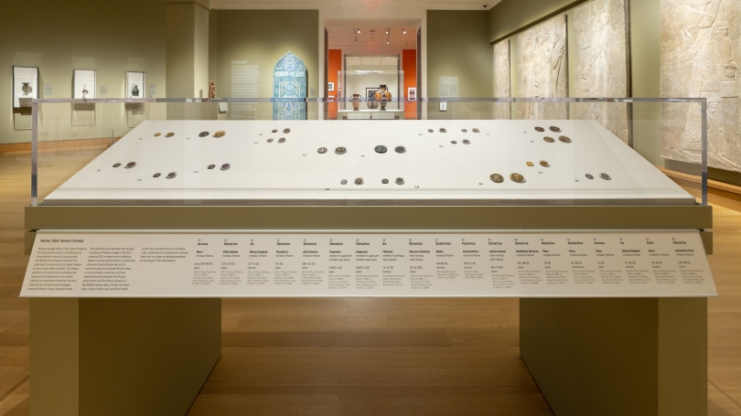 A museum gallery with a case of ancient coinage and other forms of money.