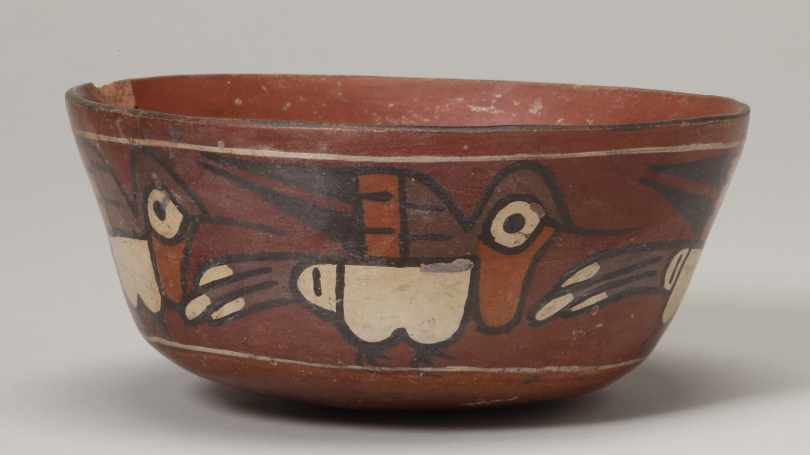 An ancient Peruvian terracotta-colored bowl depicting a group of hummingbirds. 