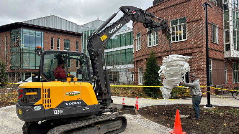 Construction crew install white sculpture.