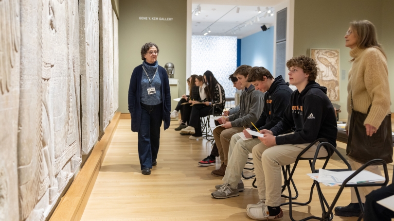 Students from Kimball Union Academy sit in front of and learn about the Assyrian Reliefs in Kim Gallery. 