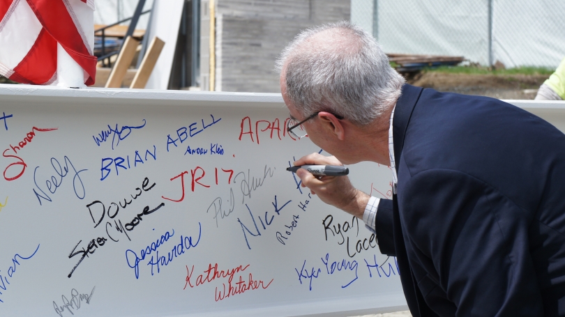 President Phil Hanlon signing the ceremonial beam at the Hood project's topping-out celebration on Friday, April 28, 2017, before the beam was put into place. Photo by Alison Palizzolo.