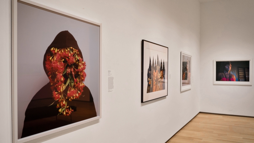 A museum gallery with white walls and contemporary photographs by Indigenous Australian artists hang on the walls.