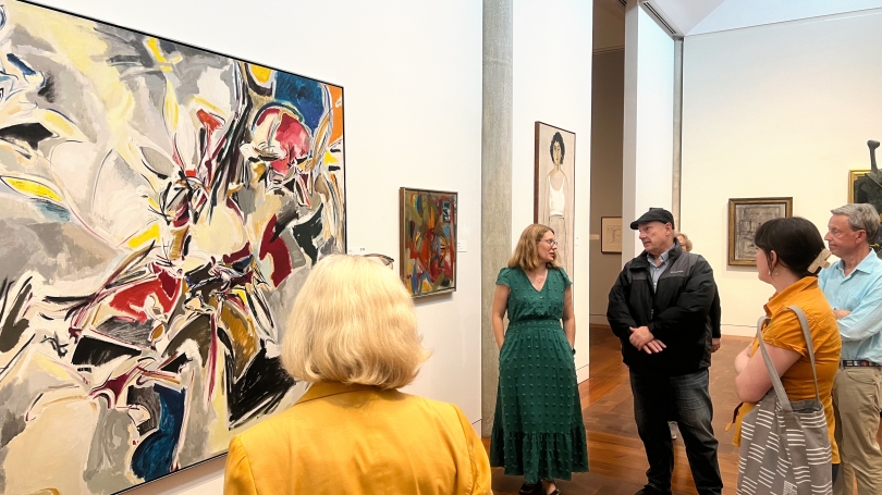 The Director's Circle experiences history and art on display at Vassar College's Loeb Museum. The group is looking at art while listening to the one of the curators at the Loeb speaking about the work on view. 