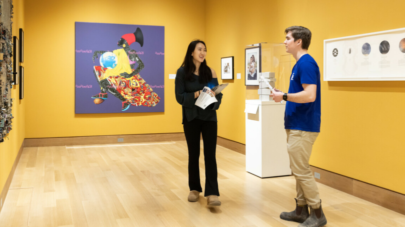 Dartmouth students explore "Knowledge Transfer" at the 2024 Winter Hood After 5 event. The walls are yellow and the student in the middle of the photo is smiling.