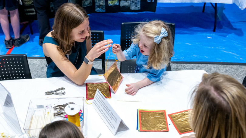 Child and Dartmouth student make art together during the Hood's Spring 2024 Community Day Event.