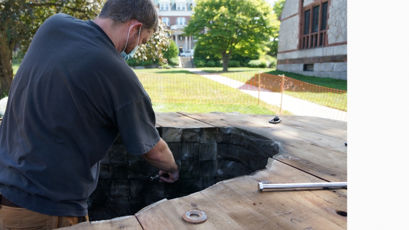 Sean Weeks-Earp from Ursula von Rydingsvard's studio conducts conservation work on von Rydingsvard's sculpture "Wide Babelki Bowl" (2007) before it was installed in front of Rollins Chapel on Dartmouth's Campus. Photo by Brian Wagner.